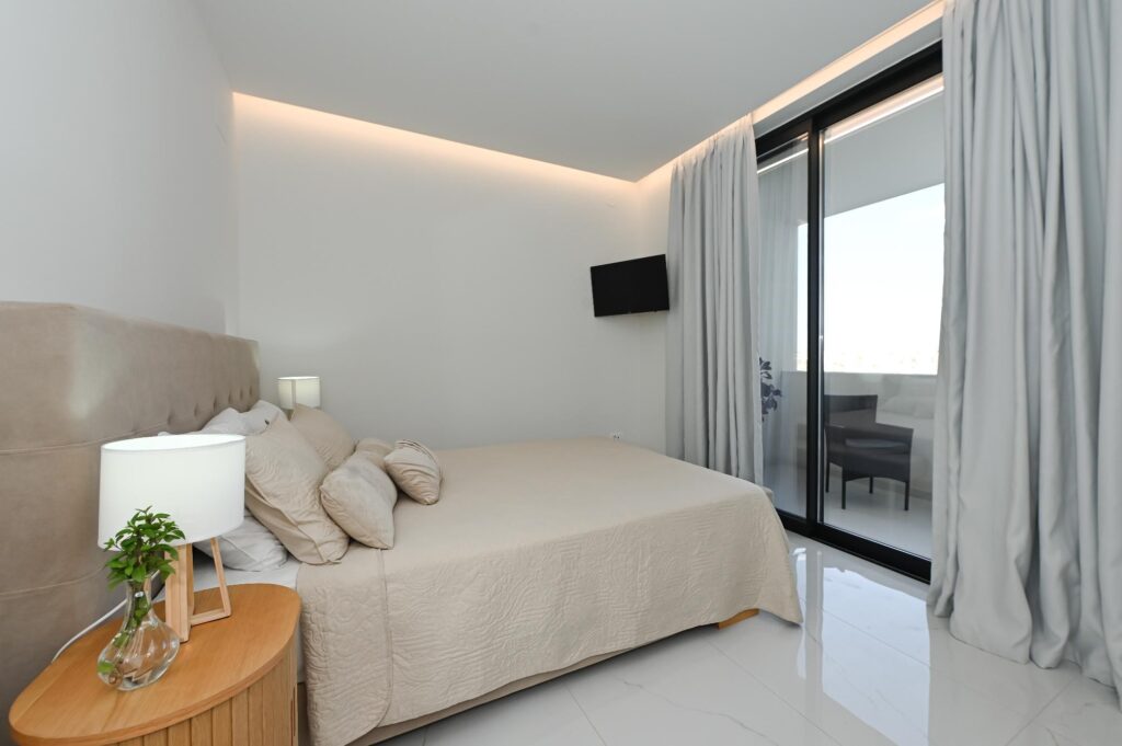 Double bedroom with balcony access and bedside lamp in the Executive Deluxe Suite