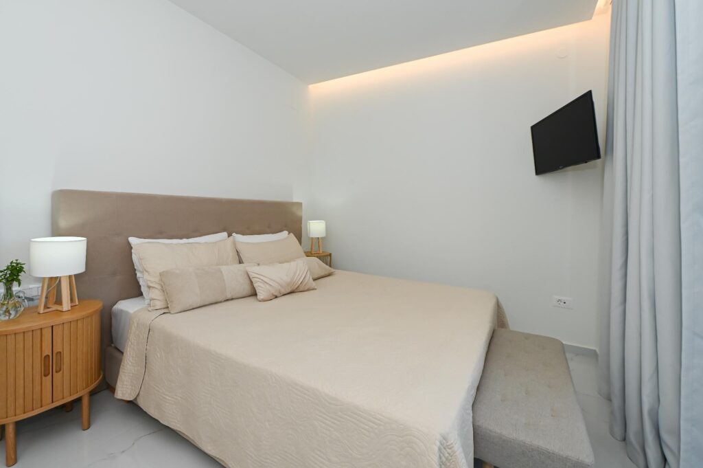 Double bed with wall-mounted TV and wooden nightstand in the Executive Deluxe Suite
